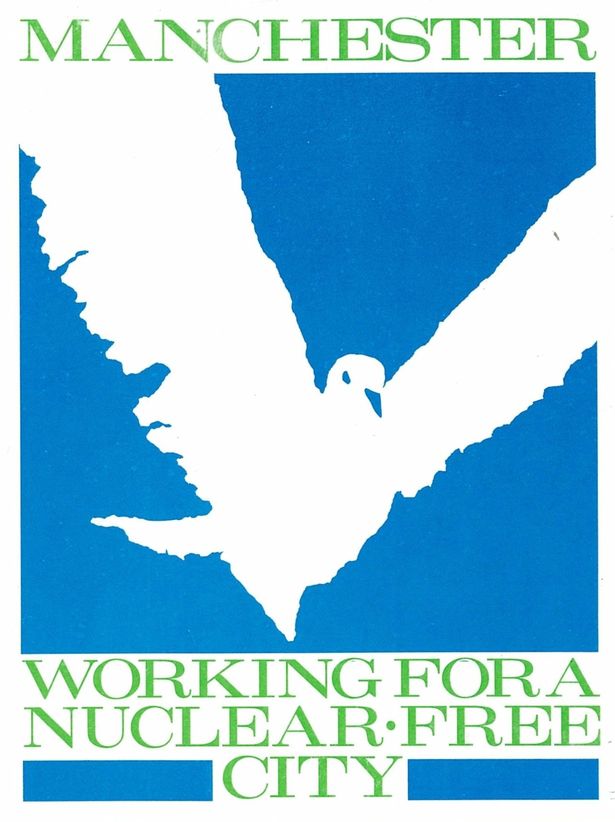 A poster saying 'Manchester: Working for a Nuclear Free City'. The text is gold and there is a white sillouhette of a dove on a blue background